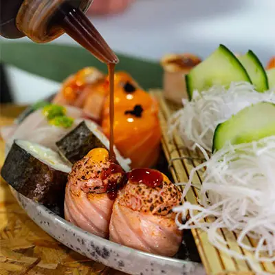 Aplicação de molho sobre peças especiais de sushi no Sushi & Restaurante Nakaza, com acabamento artesanal no momento do serviço