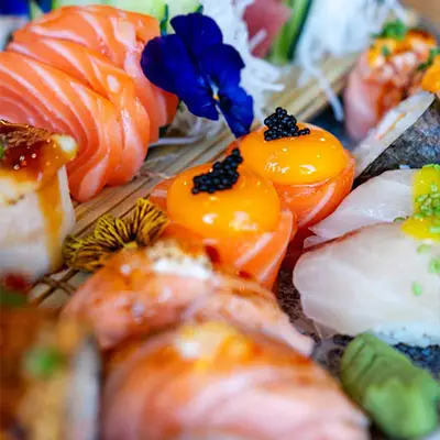 Detalhe de sushi do Sushi & Restaurante Nakaza, com sashimi de salmão, ovas e flores comestíveis