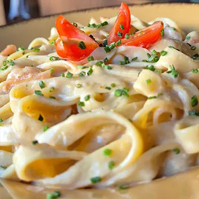 Massa à carbonara servida no Sushi & Restaurante Nakaza, com molho cremoso e topping de tomate fresco